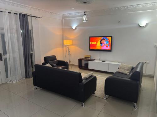 a living room with two chairs and a flat screen tv at Le coin paisible - Yaoundé, Omnisports in Yaoundé