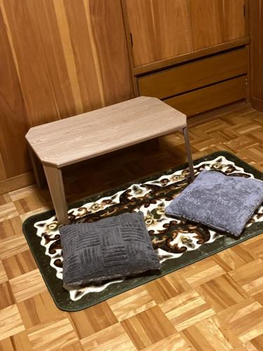 a wooden table with two pillows on a rug at いわしの子守唄 Sardine Lullaby in Matsuyama