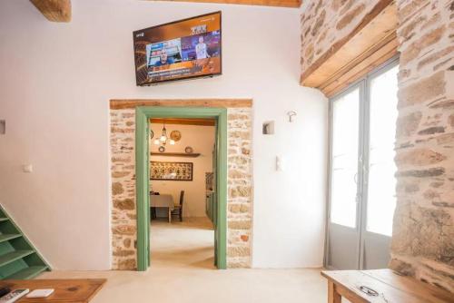 a room with a stone wall and a television on the wall at Amarantos-Traditional Village House-Apollona in Apóllona