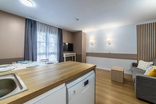 cocina y sala de estar con fregadero y sofá en Disneyland Appartements familial avec piscine intérieur chauffé, parking gratuit A 5 minutes des parcs, en Serris