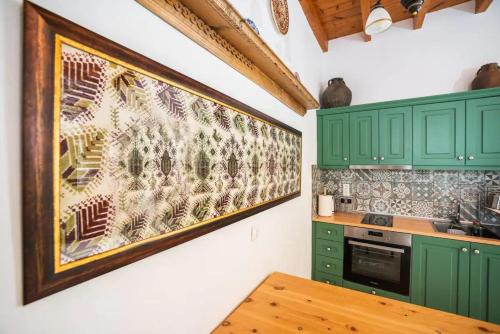 a kitchen with green cabinets and a painting on the wall at Amarantos-Traditional Village House-Apollona in Apóllona