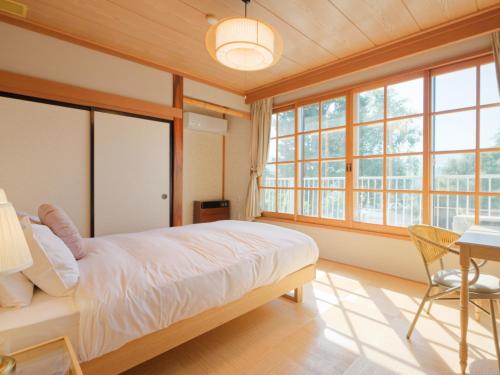 a bedroom with a bed and a table and windows at Togari Inn Suites in Iiyama