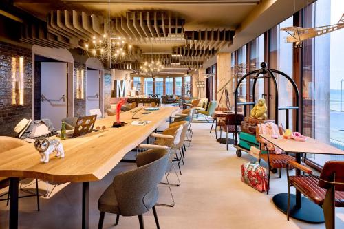 a row of tables and chairs in a room with windows at Moxy Luxembourg Airport in Luxembourg