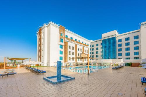 a resort with a pool and tables and chairs and buildings at Four Points by Sheraton Al Ain in Al Ain