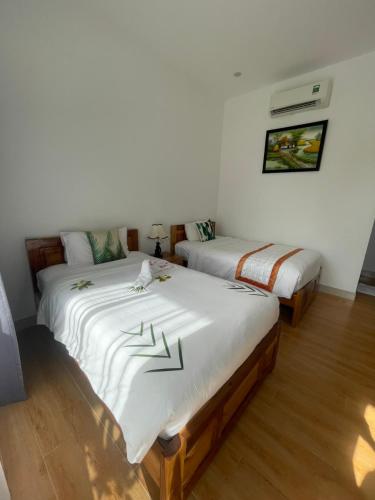 two beds in a room with white sheets at Aurora House in Phu Quoc