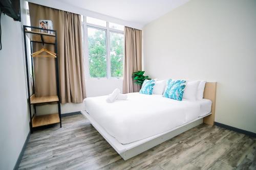 Una cama blanca en una habitación con ventana. en Swing & Pillows - Putrajaya Selangor, en Putrajaya