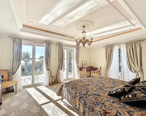 - une grande chambre avec un grand lit et un lustre dans l'établissement Palace de Lys, à Cannes