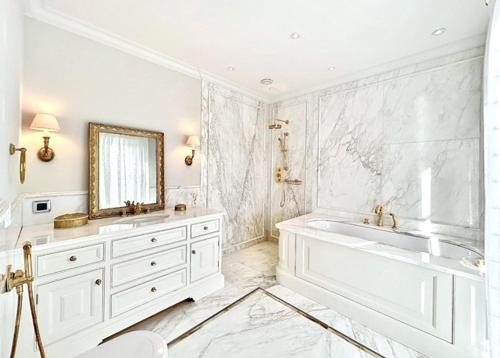 une salle de bain blanche avec une baignoire et un miroir dans l'établissement Palace de Lys, à Cannes