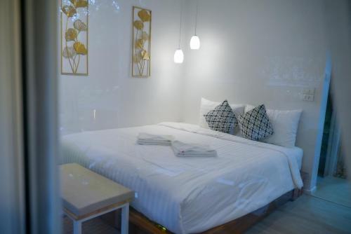 a white bed with pillows and a table in a room at Arb Pa Home and Cafe @ Mae on in Chiang Mai