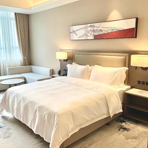 a bedroom with a large white bed and a couch at Guangzhou Southern Airlines Pearl Airport Hotel- Free shuttle bus to airport in Guangzhou