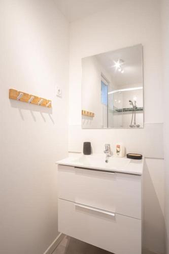 une salle de bain blanche avec un lavabo et un miroir dans l'établissement Le Saphir - 150m de la Plage, à Étretat