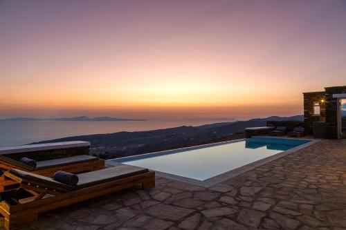 a villa with a view of the ocean at sunset at Villa Leonora Tinos in Arnados