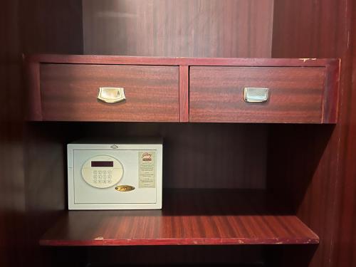 a wooden shelf with a microwave and a drawer at Ananya Comfortss in Hospet