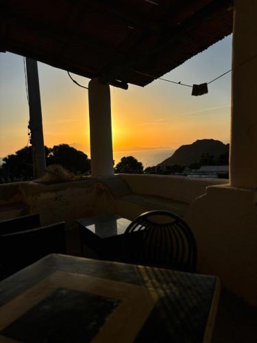 a sunset from a patio with a table and chair at Villa La Rosa in Filicudi