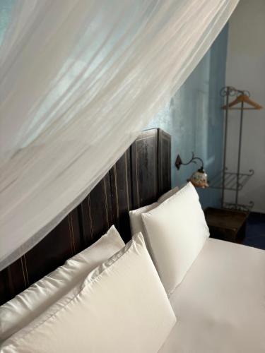 a bed with two white pillows and a canopy at Villa La Rosa in Filicudi