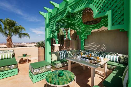 a patio with green furniture and a table at Riad Due in Marrakech