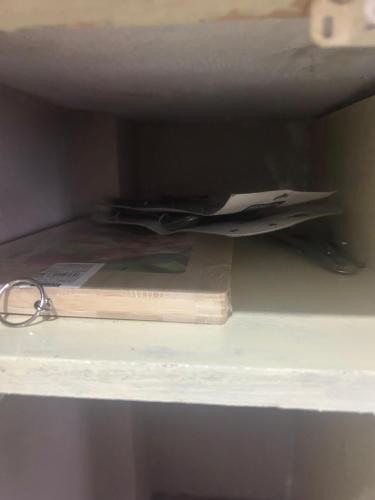 a shelf with a book and a pair of papers at Serenity Homestay Shillong in Shillong