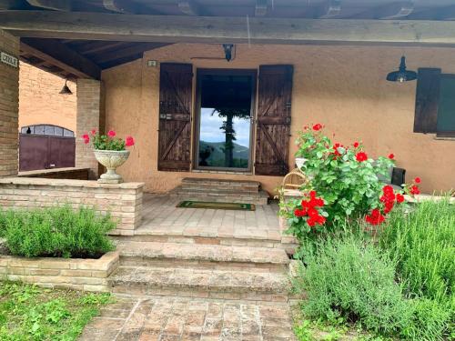 a front door of a house with red flowers at Val di Codena - Holiday Home in Vetto