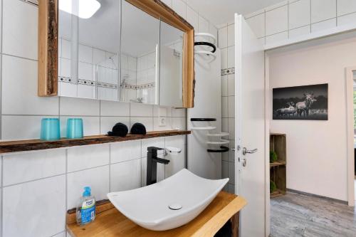 Villa Eichwald Appartements في فرودنستاد: حمام أبيض مع حوض ومرآة