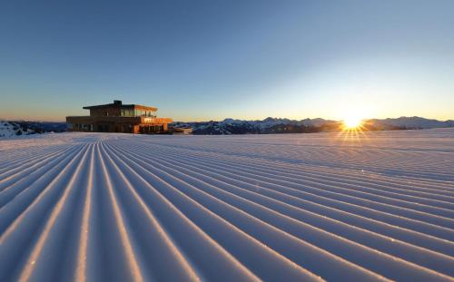 a field covered in snow with the sun in the background at DAS EDELWEISS - Salzburg Mountain Resort in Grossarl