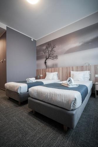 two beds in a bedroom with a painting on the wall at Hotel Picaro Kopytkowo A1 in Kopytkowo