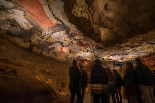 a group of people looking at a painting in a cave at Lumineux in Le Bugue