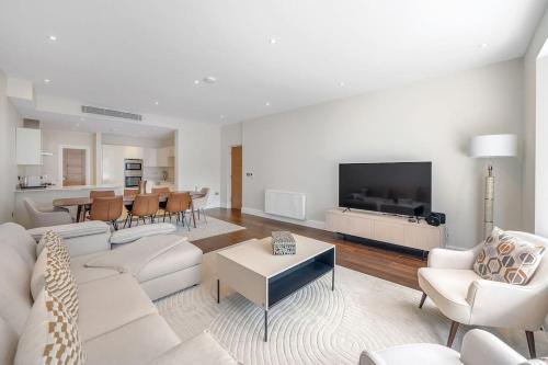a living room with white furniture and a flat screen tv at New 3Bed in Knightsbridge in London
