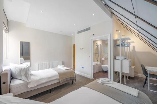 a white bedroom with two beds and a table at New 3Bed in Knightsbridge in London