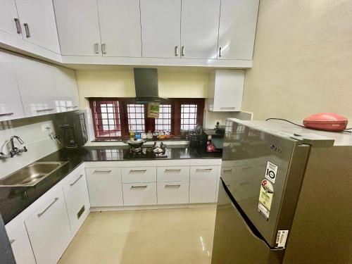 a kitchen with white cabinets and a black refrigerator at Krishnakripa - Luxury Private Villa Near Guruvayoor Temple in Guruvāyūr
