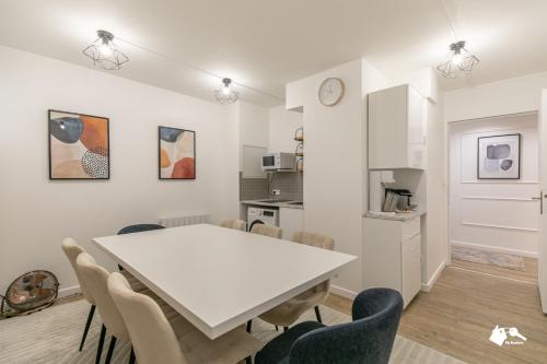 une cuisine et une salle à manger avec une table et des chaises blanches dans l'établissement MBA - Beslay - Splendide Appartement Paris Centre, à Paris