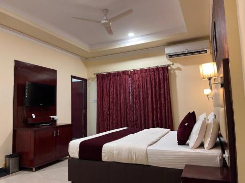 a hotel room with a bed and a television at Ananya Comfortss in Hospet