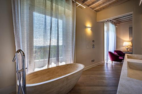 a large bath tub in a bathroom with a window at Luxury Villa Tolomei Gucci with spa in San Jacopo al Girone