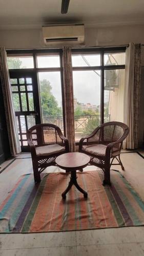 a room with two chairs and a table in front of a window at Basti House - Boutique Homestay in Lucknow