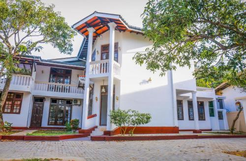 a large white building with trees in front of it at alBum by sEa World in Matara