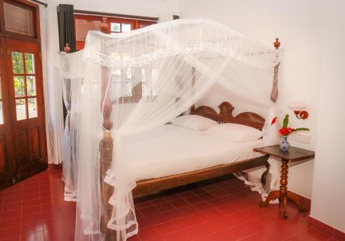 a bedroom with a bed with mosquito netting at alBum by sEa World in Matara