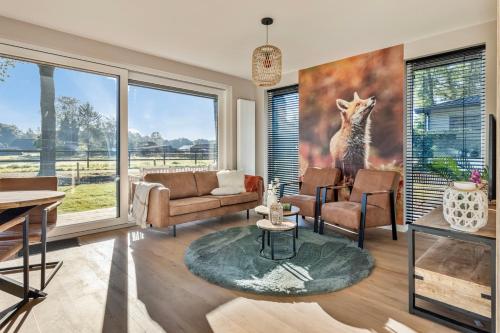 a living room filled with furniture and a large window at 'Lodge de Vos' luxe en vrijstaande lodge bij het Speulder- en Spielderbos in Putten