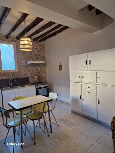 une cuisine avec des armoires blanches et une table et des chaises dans l'établissement Duplex en centre ville, à Villers-Cotterêts