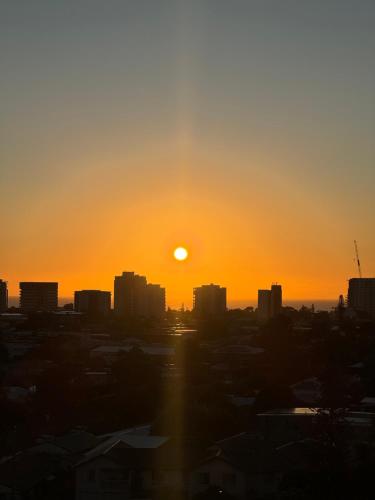 a sunset over a city with the sun setting at Sunshine Coast Paradise in Maroochydore