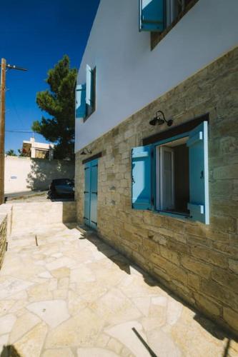 a stone building with blue windows and a stone sidewalk at Dipaton House in Vasa 1 in Limassol