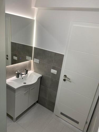 a white bathroom with a sink and a shower at Luxury Pyramid Apartment Visoko in Visoko