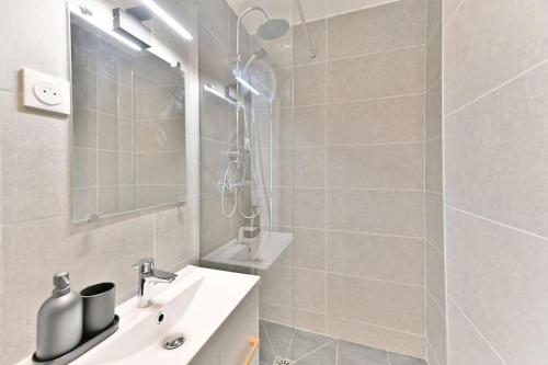 une salle de bain blanche avec une douche et un lavabo dans l'établissement Studio tout équipé à Montreuil proche Paris - II, à Montreuil