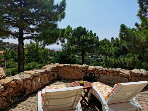 a table and chairs on a patio with a stone wall at Villa Pol & Dod - Piscine et vue sublime in Monacia-dʼAullène