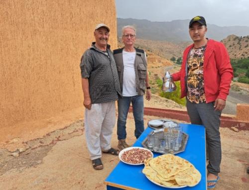 three people standing next to a table with food on it at GITE ROURAL TATIOUINE Midelt in Tattiouine