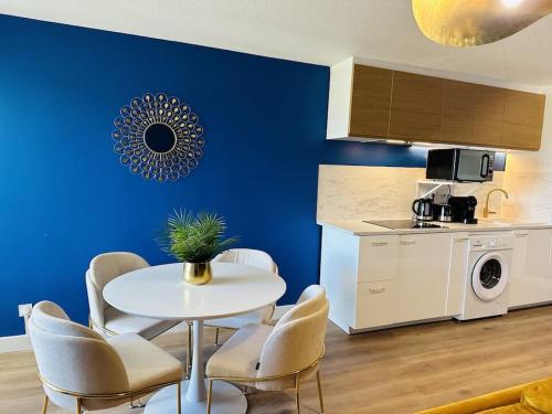 une cuisine avec une table et des chaises et un mur bleu dans l'établissement You&Me, à Narbonne