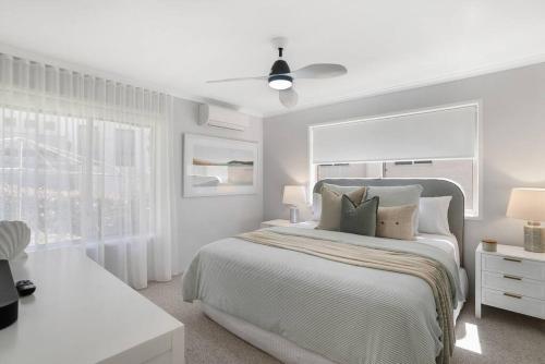 a white bedroom with a bed and a ceiling fan at Miami Getaway in Gold Coast