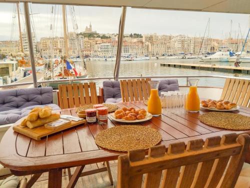 une table en bois avec des assiettes de nourriture et de jus d'orange dans l'établissement Yacht idéalement situé au coeur du Vieux-Port, à Marseille