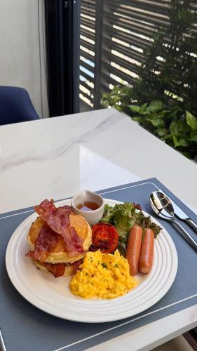 a plate of breakfast food with eggs bacon and vegetables at GM Estate Hotel and Executive Apartments Sukhumvit 20 in Bangkok