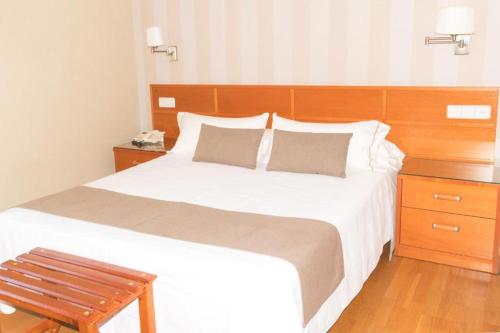 a bedroom with a large white bed with a wooden headboard at Hotel A Queimada in Nigrán