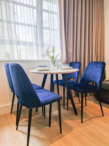 a table with four blue chairs and a table with a vase at 3-Bedroom with Balcony and Studio Apartments in St Johns Wood near Marylebone & Regents Park by Staylio London in London