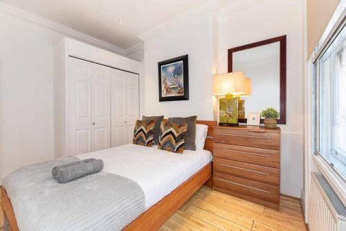 a bedroom with a bed with a mirror and a dresser at Discover London Central 2 Bedroom in Kensington in London